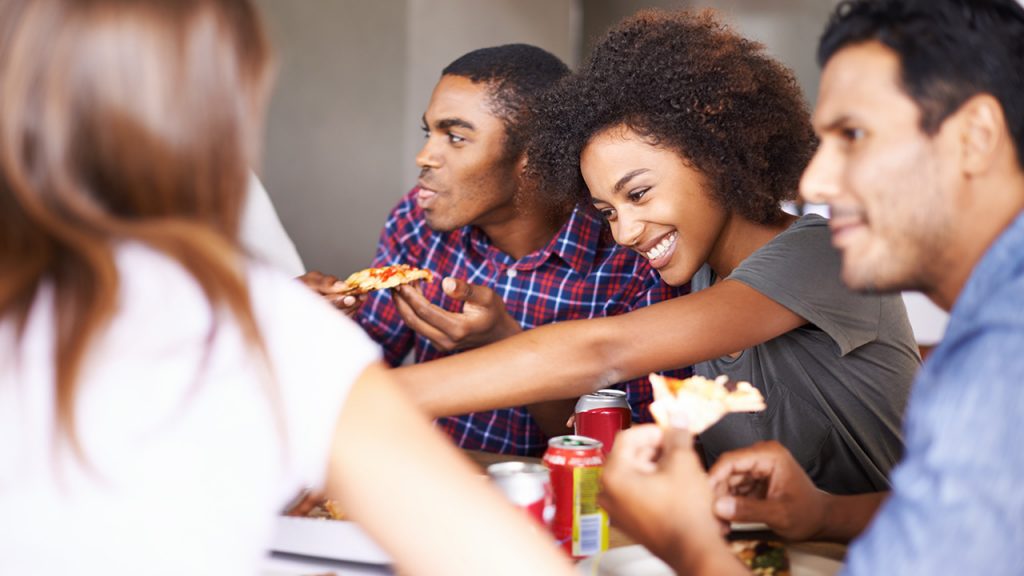 Teen grabbing a slice of pizza while smiling